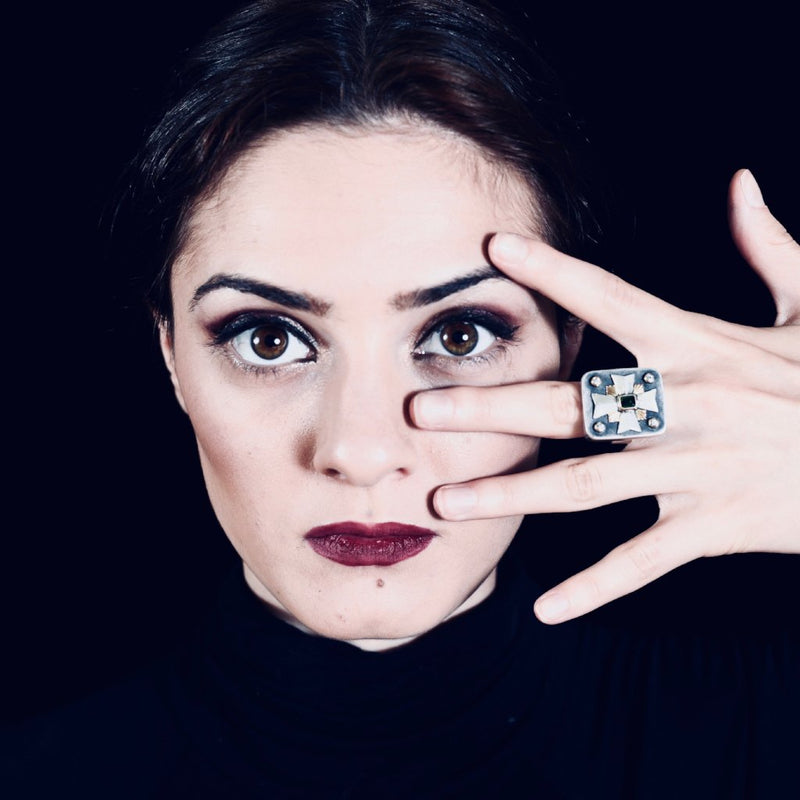 Woman wearing a Maltese Cross Ring with Diamonds and a green gemstone